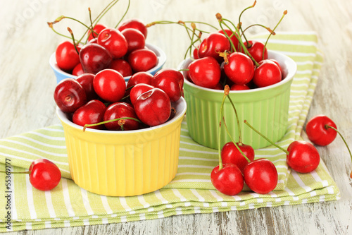 Photo: Cherry berries in bowls on wooden table close up Cherry berries in bowls on wooden table close up