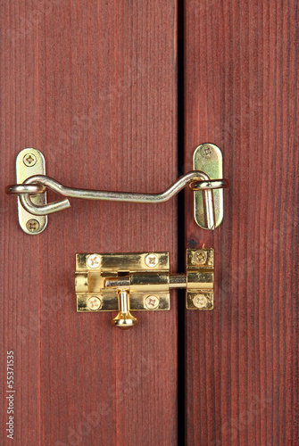 Photo: Metal hook and deadbolt in wooden door close-up Metal hook and deadbolt in wooden door close-up