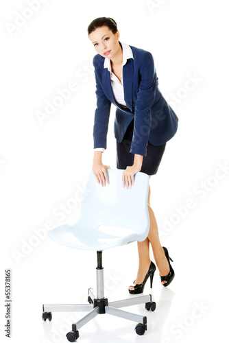Photo: Beautiful successful businesswoman standing next to ofice chair Beautiful successful businesswoman standing next to ofice chair