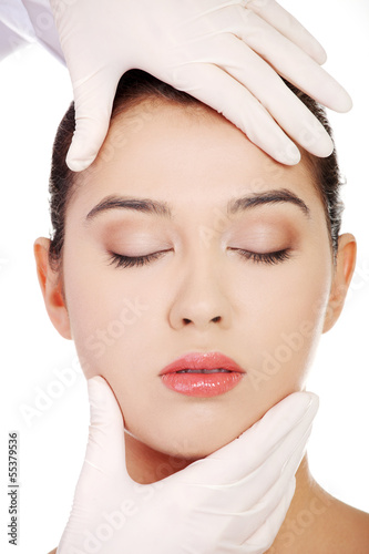Photo: Doctor hands in gloves touching the beautiful woman face. Doctor hands in gloves touching the beautiful woman face.