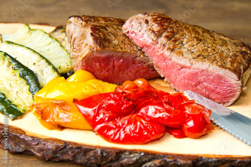 Photo: Delicious beef steaks on wooden table Delicious beef steaks on wooden table