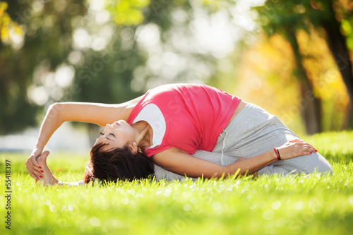 Photo: Pretty woman doing yoga exercises in the park Pretty woman doing yoga exercises in the park