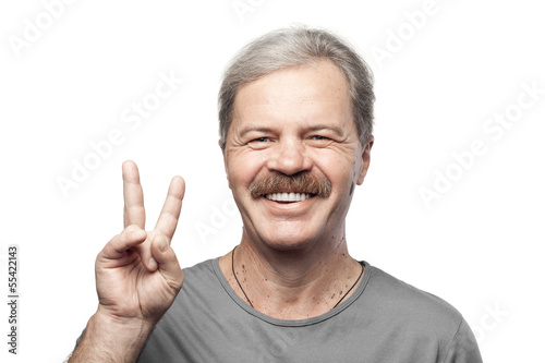 Photo: smiling mature man showing victory sign isolated on white backgr smiling mature man showing victory sign isolated on white backgr