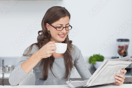 Photo: Woman holding a cup of coffee and reading a newspaper Woman holding a cup of coffee and reading a newspaper