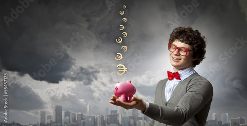 Photo: Young businessman holding moneybox Young businessman holding moneybox