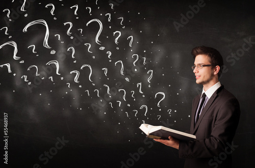 Photo: Young man reading a book with question marks coming out from it Young man reading a book with question marks coming out from it