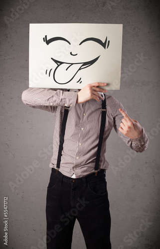 Photo: Businessman holding a paper with funny smiley face in front of h Businessman holding a paper with funny smiley face in front of h