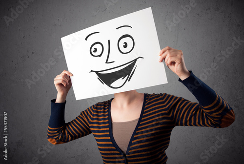 Photo: Woman holding a cardboard with smiley face on it in front of her Woman holding a cardboard with smiley face on it in front of her