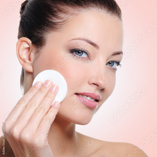 Photo: Woman cleaning her face with cotton swab Woman cleaning her face with cotton swab