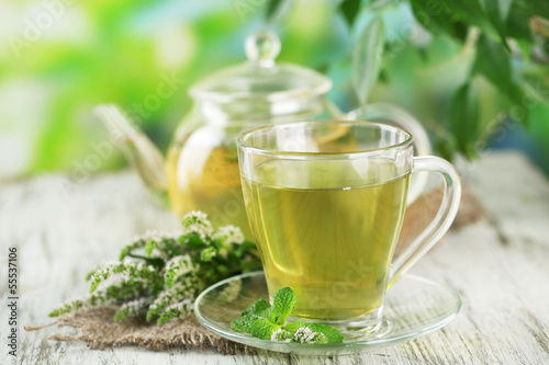 Photo: Teapot and cup of herbal tea with fresh mint flowers Teapot and cup of herbal tea with fresh mint flowers