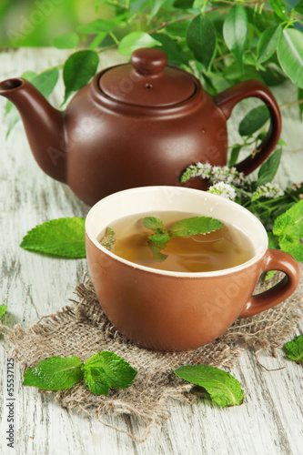 Photo: Teapot and cup of herbal tea with fresh mint flowers Teapot and cup of herbal tea with fresh mint flowers