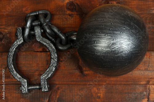Photo: Ball and chain on wooden background Ball and chain on wooden background