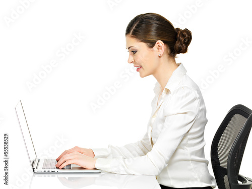 Photo: woman sits from the table and working on laptop woman sits from the table and working on laptop