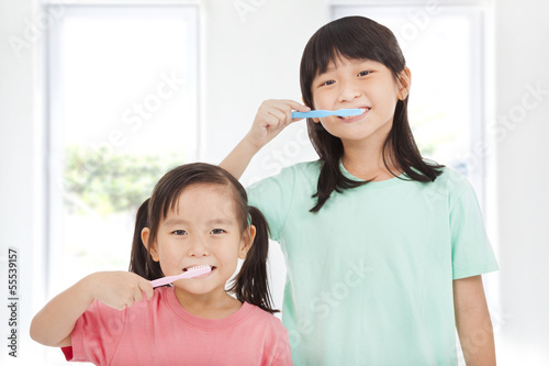 Photo: two happy little girls brushing her teeth two happy little girls brushing her teeth