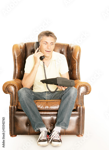 Photo: Mann telefoniert auf einem Sessel Mann telefoniert auf einem Sessel