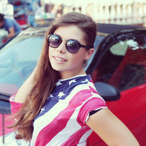 Photo: Pretty American girl in American flag t-shirt. Portrait outdoors Pretty American girl in American flag t-shirt. Portrait outdoors