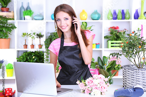 Photo: Beautiful girl florist with flowers in flowers shop Beautiful girl florist with flowers in flowers shop