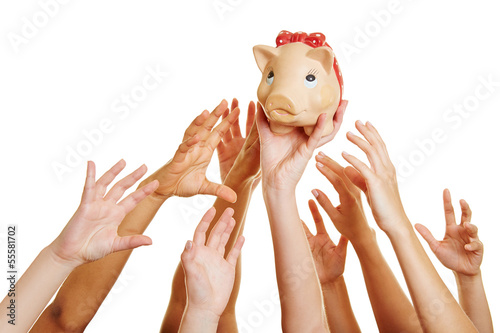 Photo: Hands reaching for money in piggy bank Hands reaching for money in piggy bank
