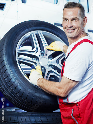 Photo: Auto mechanic changes car tyres in a garage Auto mechanic changes car tyres in a garage
