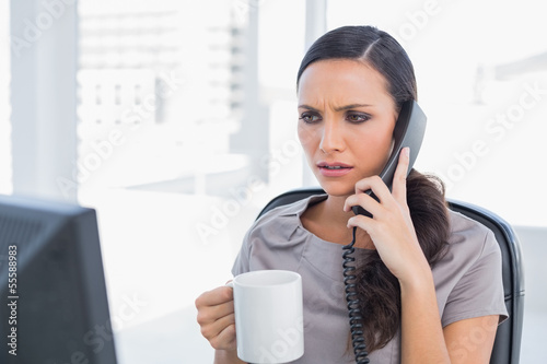 Photo: Frowning secretary answering phone Frowning secretary answering phone