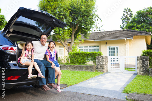 Photo: happy family sitting in the car and their house behind happy family sitting in the car and their house behind