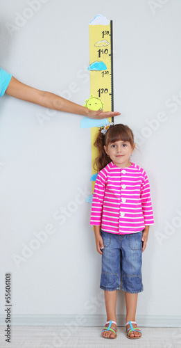 Photo: Mom measures growth of daughter in room Mom measures growth of daughter in room
