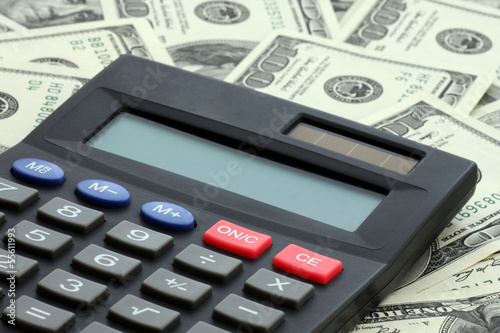 Photo: calculator on heap of one hundred dollars banknotes calculator on heap of one hundred dollars banknotes