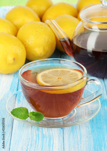 Photo: Cup of tea with lemon on table on blue background Cup of tea with lemon on table on blue background
