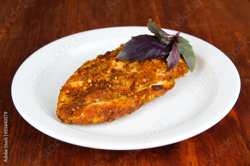 Photo: Roasted chicken fillets on white plate, on wooden background Roasted chicken fillets on white plate, on wooden background