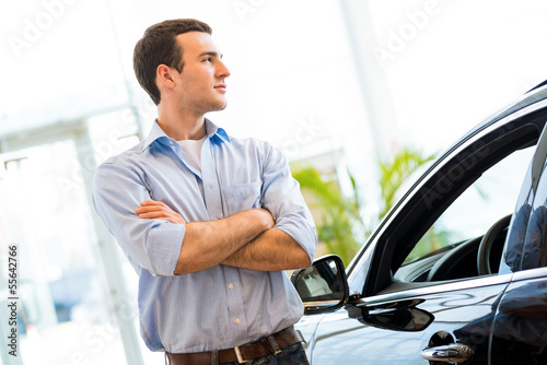 Photo: man standing near a car man standing near a car