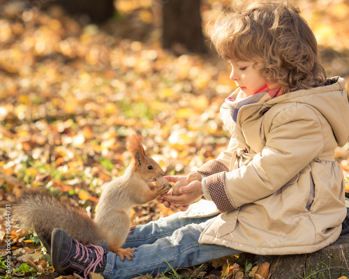 Photo: Child feeds a little squirrel Child feeds a little squirrel
