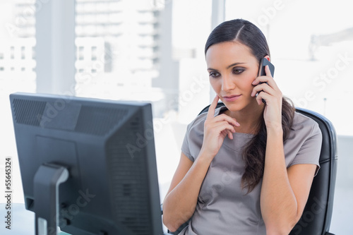 Photo: Thoughtful attractive businesswoman having a phone conversation Thoughtful attractive businesswoman having a phone conversation