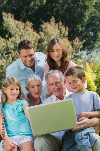 Photo: Multi generation family with a laptop sitting in park Multi generation family with a laptop sitting in park