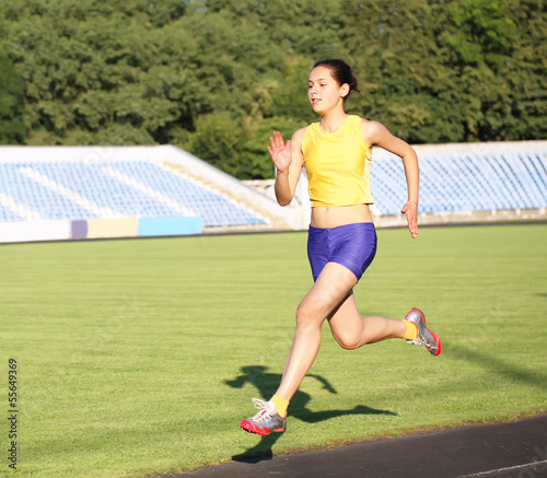 Photo: Girl running on the stadium track Girl running on the stadium track