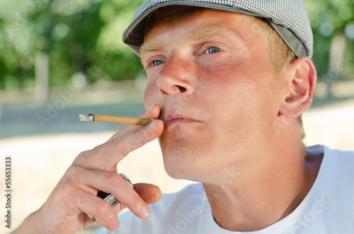 Photo: Thoughtful middle-aged man smoking in the park Thoughtful middle-aged man smoking in the park
