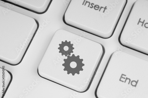 Illustration: Cogwheels on white keyboard close-up. Cogwheels on white keyboard close-up.