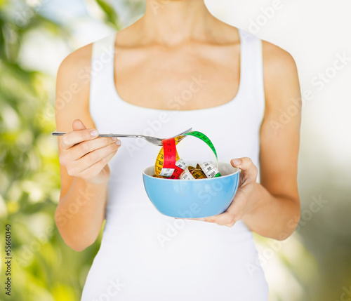 Photo: woman hands holding bowl with measuring tape woman hands holding bowl with measuring tape