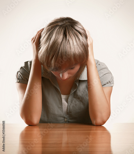 Photo: A young tired woman sitting at the desk A young tired woman sitting at the desk