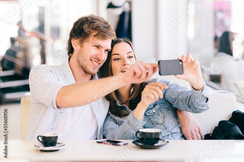 Photo: Couple taking photo of themselves with a phone in cafe Couple taking photo of themselves with a phone in cafe