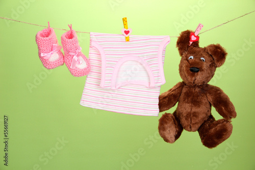 Photo: Baby clothes hanging on clothesline, on color background Baby clothes hanging on clothesline, on color background