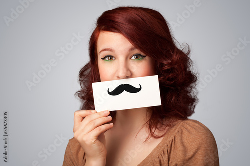 Photo: Happy cute girl holding paper with mustache drawing Happy cute girl holding paper with mustache drawing