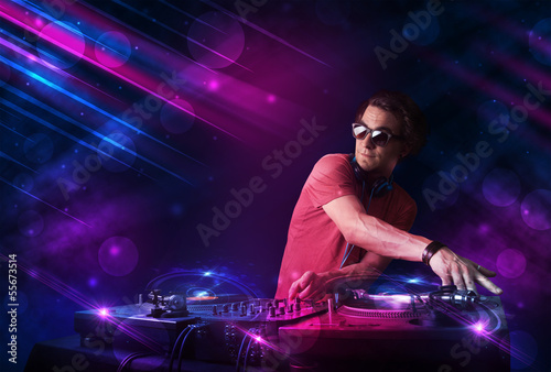 Photo: Young DJ playing on turntables with color light effects Young DJ playing on turntables with color light effects