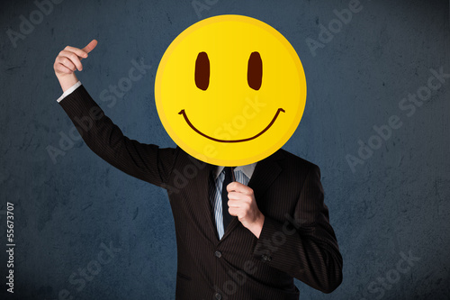 Photo: Businessman holding a smiley face emoticon Businessman holding a smiley face emoticon