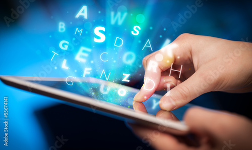 Photo: Finger pointing on tablet pc, letters concept Finger pointing on tablet pc, letters concept