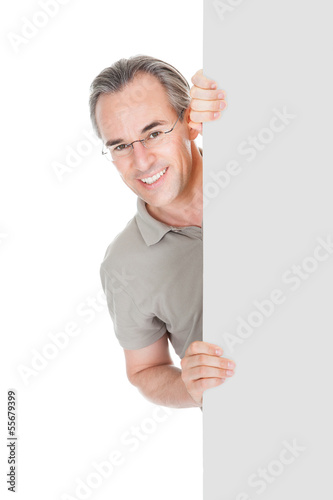 Photo: Happy Mature Man Standing Behind Placard Happy Mature Man Standing Behind Placard