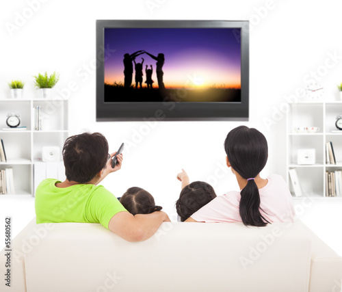 Photo: family watching the tv in living room family watching the tv in living room