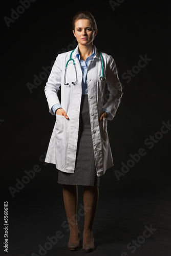 Photo: Full length portrait of doctor woman isolated on black Full length portrait of doctor woman isolated on black