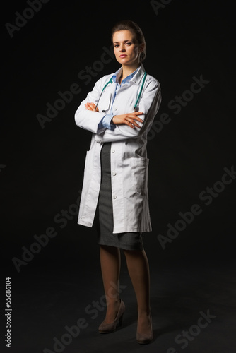 Photo: Full length portrait of serious doctor woman on black background Full length portrait of serious doctor woman on black background