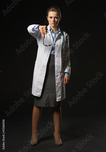 Photo: Full length portrait of doctor woman showing thumbs down Full length portrait of doctor woman showing thumbs down