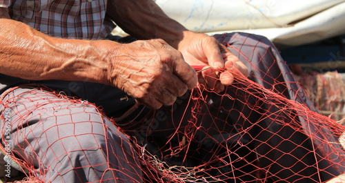 Photo: Mani al lavoro su una rete da pesca Mani al lavoro su una rete da pesca